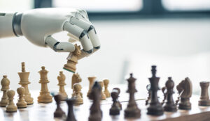 A robot hand plays picks up a white chess piece