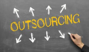 The word outsourcing is written on a blackboard in yellow chalk
