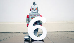 A small robot toy holds the number 6