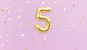 A photo of a gold balloon in the shape of the number 5