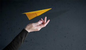 A picture of a paper plane being guided by a hand