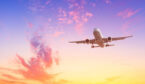 Airplane flying above clouds during sunset