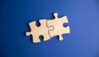 Partnership concept with two pieces of wood jigsaw puzzle on a blue background