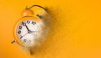 Dissolving orange alarm clock. Reducing time concept