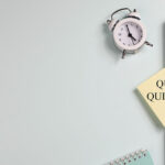 'Quiet quitting' on yellow sticker on computer with clock and notebook.