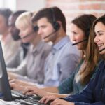 6 call centre agents with headsets on talking