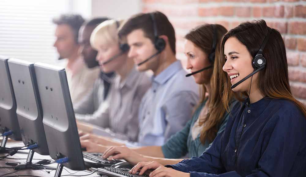 6 call centre agents with headsets on talking