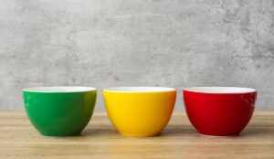 Green, yellow and red bowls on wooden background