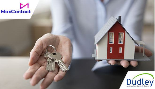 Person holding house keys in one hand and a miniature house in the other