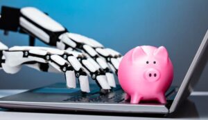 Robotic Hand Using Laptop With Pink Piggybank On Keypad