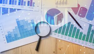 Magnifying glass and documents with analytics data lying on table