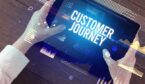 Close-up of hands holding tablet with CUSTOMER JOURNEY inscription