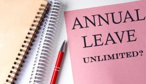 ANNUAL LEAVE UNLIMITED? on pink paper with office tools on white background