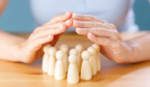 Close up shot of a woman hand guarded protect wooden people on table